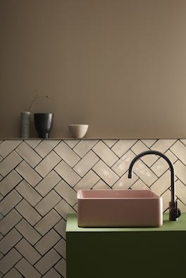 Bathroom  painted in warm neutral Rolling Fog with off white tiles underneath and a pink and green color block sink.