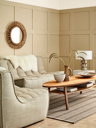 Paneled living space painted in warm neutral 'Travertine' with two sofas and a wooden coffee table.