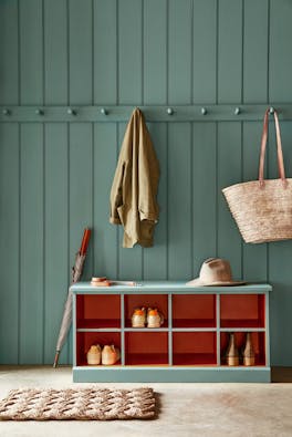 Paneled mudroom painted in green shade, Pleat, with contrasting deep red (Heat) shelving.