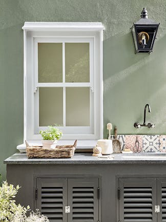 Outside kitchen sink area in grey green 'Boringdon Green' with a contrasting grey cabinet and white window frame.