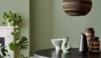 Dining area with the walls painted in calming Sage Green with a black table, stools and a chair.