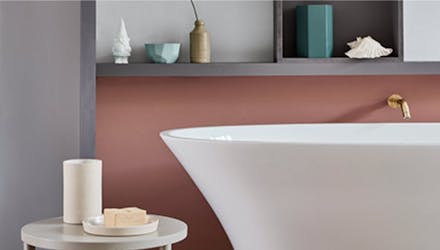 Close-up bathtub in front of a wall with the lower half in a muted pink (Blush) and the upper wall in grey (Gauze - Dark).