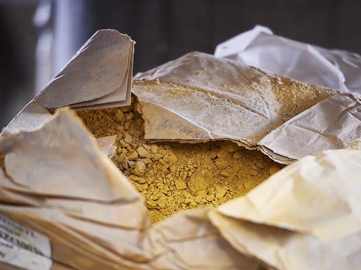 Close-up of a brown paper bag that has been ripped open, revealing golden yellow powder inside.