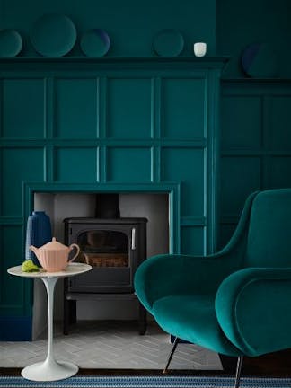 Living space featuring walls and paneling painted in dark green (Mid Azure Green), a matching velvet sofa and a stripy rug.