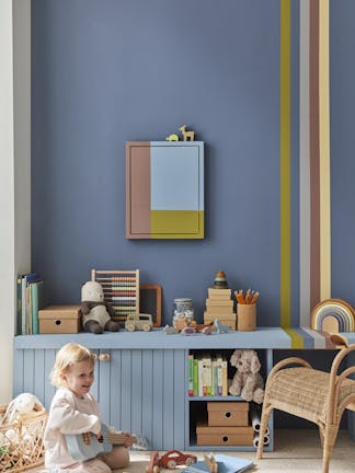 Child's playroom painted in dark blue (Juniper Ash) with multi colored stripes on the right, and toys placed on top of a unit with a child playing guitar.