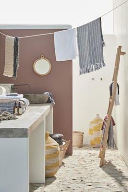 Outside yard space with the left wall painted in neutral red shade 'Nether Red' and the right wall in off-white 'Linen Wash' with a stone worktop and laundry hanging above.