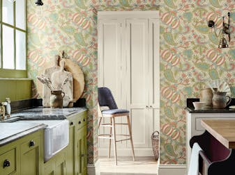 "Kitchen with bright green cabinets (Citrine) and a paisley wallpaper (Pomegranate - Bazaar) with a wooden floor and rug."