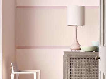 Close-up of a pale pink wall painted in 'Dorchester Pink - Pale' and a matching colored lampshade in the front.