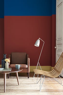 Living room painted in primary colors, red, blue and yellow with an armchair and a wooden table.