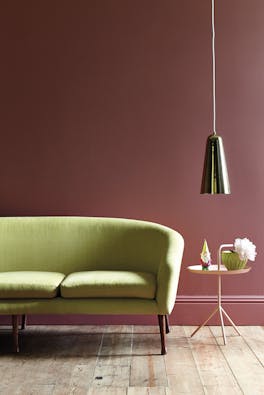 Living room painted in mid pink shade 'Ashes of Roses' with a lime green sofa on a wooden paneled floor.