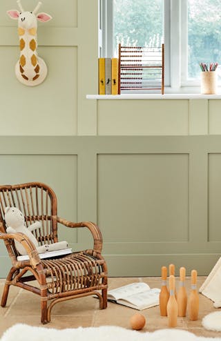 Nursery with an earthy green panelled wall (Green Stone and Green Stone - Light) and a wooden chair and tipi in front.