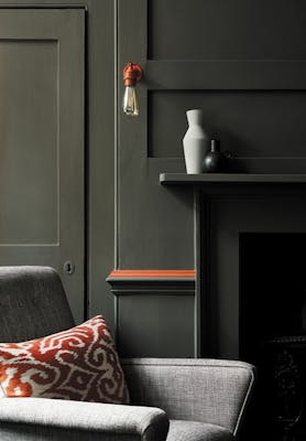 Living room color drenched in grey/ green shade 'Pompeian Ash' with a deep red contrast stripe and a grey sofa.