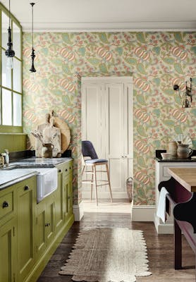 Kitchen with bright green cabinets (Citrine) and a paisley wallpaper (Pomegranate - Bazaar) with a wooden floor and rug.