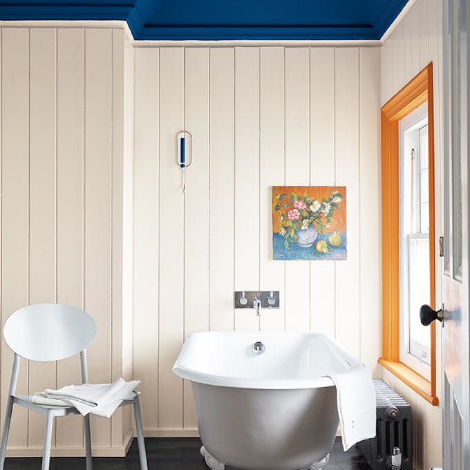 Panelled bathroom with white walls, a dark blue ceiling (Deep Space Blue) and accent window frame, painted Marigold orange.