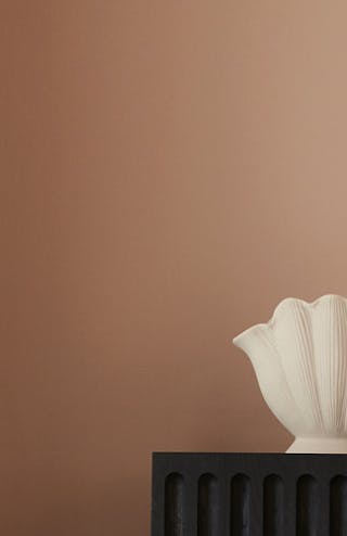 Close-up of two walls in varying neutral pink shades of Masquerade, alongside abstract artwork and ornament.