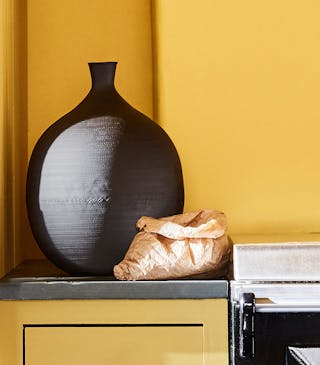 Close-up of kitchen walls and cupboard doors drenched in the vibrant yellow shade 'Giallo'.