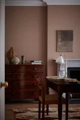 Home office space painted in muted pink shade 'Mochi' with a wooden chest of drawers, desk and chair.