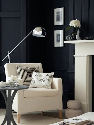 Sitting room with Jack Black walls, white fireplace and armchair, silver lamp and grey (Dark Lead Colour) side table.