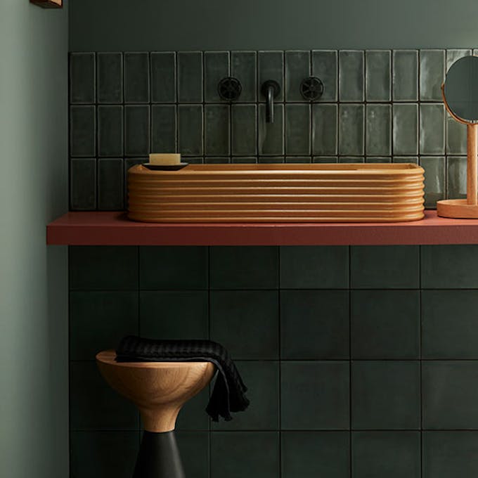 Tiled bathroom painted in grey green shade 'Livid', with contrasting sink, stool and mirror.