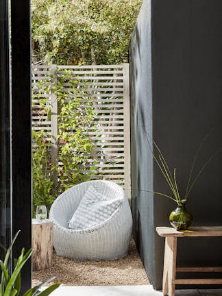 Dark Obsidian Green exterior walls next to a grey basket seat alongisde wooden side tables.