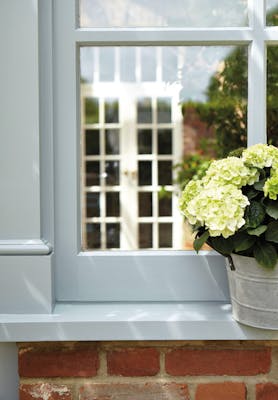 Exterior window painted in grey blue 'James' with a potted plant on the windowsill.