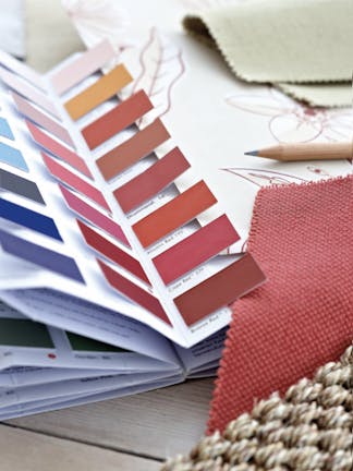 Close-up of a Little Greene Color Card open, showing red, pink and blue color swatches next to wallpaper and fabric samples.