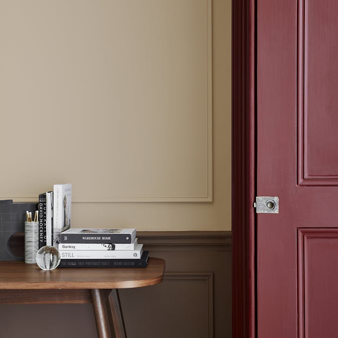 Warm neutral (Castell Pink) home study area with a red (Arras) door next to a wooden desk.