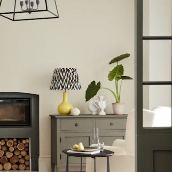 Neutral living space painted in 'Portland Stone' with grey drawers, fireplace and an armchair.