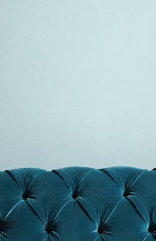 Close-up of a two-tone blue wall painted in Celestial Blue and Marine Blue with a coordinating blue velvet couch in front.