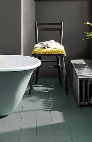 Bathroom painted in dark grey 'Vulcan' with contrasting grey, green (Livid) details with a bathtub, chair and window.