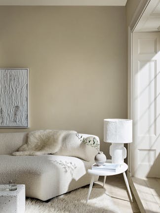 Living room in 3 different neutral shades (Silent White) with a sofa, table and lamp next to a window.