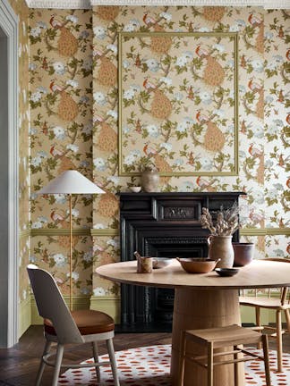 Dining room with metallic bird print wallpaper (Pavona - Gina) and a wooden dining table and chairs in front of a fireplace.