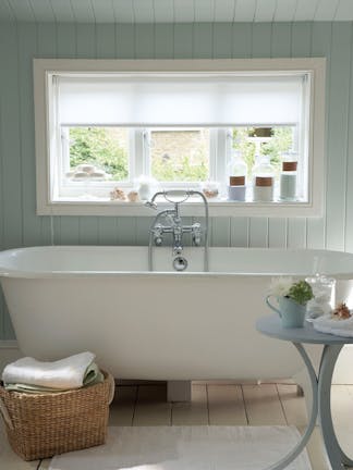 Paneled bathroom painted in light green (Salix) with a white bathtub under a large window.