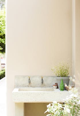 Outside sink area painted in warm neutral Silent White - Deep with a small green gnome and plants.