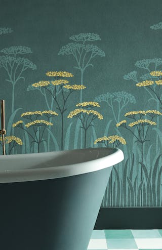 Close-up of green floral mural wallpaper with yellow accents (Achillea - Aurora) behind a dark green (Harley Green) bathtub.