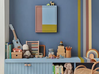 Children's playroom with a warm blue Juniper Ash painted wall with bright stripes and a shelf full of toys.