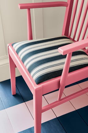 Dark pink (Carmine) chair with a dusky pink stripe painted from the wall down to the navy blue panelled floor.