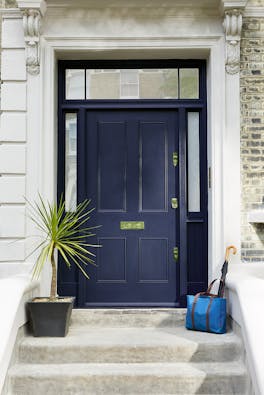 Front door painted in blue black 'Basalt' at the top of stone steps with a potted plant.