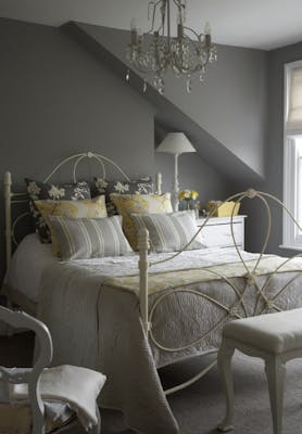 Bedroom painted in mid gray shade 'Lead Color' and lighter grey 'French Grey' with a double bed covered in cushions.