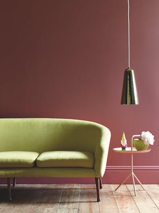 Living room painted in mid pink shade 'Ashes of Roses' with a lime green sofa on a wooden paneled floor.