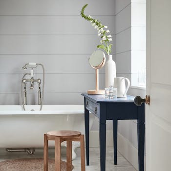 Bathroom painted in dark grey (Gauze - Dark) with a white bathtub and contrasting blue black (Basalt) side table.