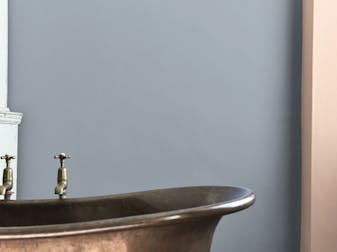 Close-up of a bathroom with a metallic bath and blue wall.