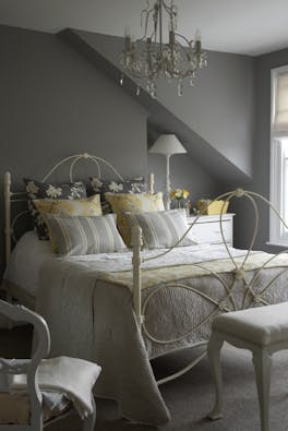 Bedroom painted in mid gray shade 'Lead Color' and lighter grey 'French Grey' with a double bed covered in cushions.