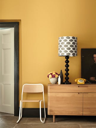 Hallway painted in mustard yellow (Yellow-Pink) with a wooden side table and chair.