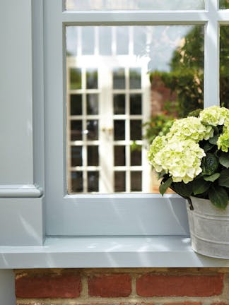 Exterior window painted in grey blue 'James' with a potted plant on the windowsill.