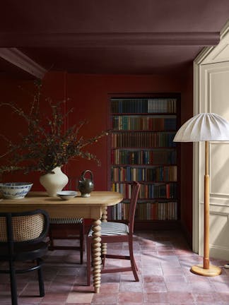 Dining room painted in cherry red shade 'Bronze Red' with a crimson ceiling (Arras) above wooden dining furniture and a book shelf.