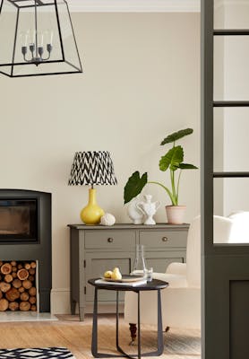 Neutral living space painted in 'Portland Stone' with grey drawers, fireplace and an armchair. 