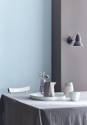 Dining room painted half in blue grey (Arquerite) and half in light blue (Pale Wedgwood) with a table and crockery on top.