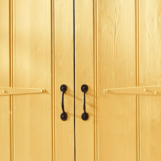 Close-up of wooden cupboard doors painted in the vibrant yellow wall shade 'Giallo'.