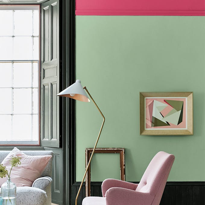 Living room painted in light green 'Pea Green' with a bright pink contrast stripe and pale pink chair.